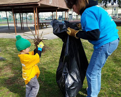 Community - Strickler Insurance Team Member Cleaning Up In The Community With Young Boy