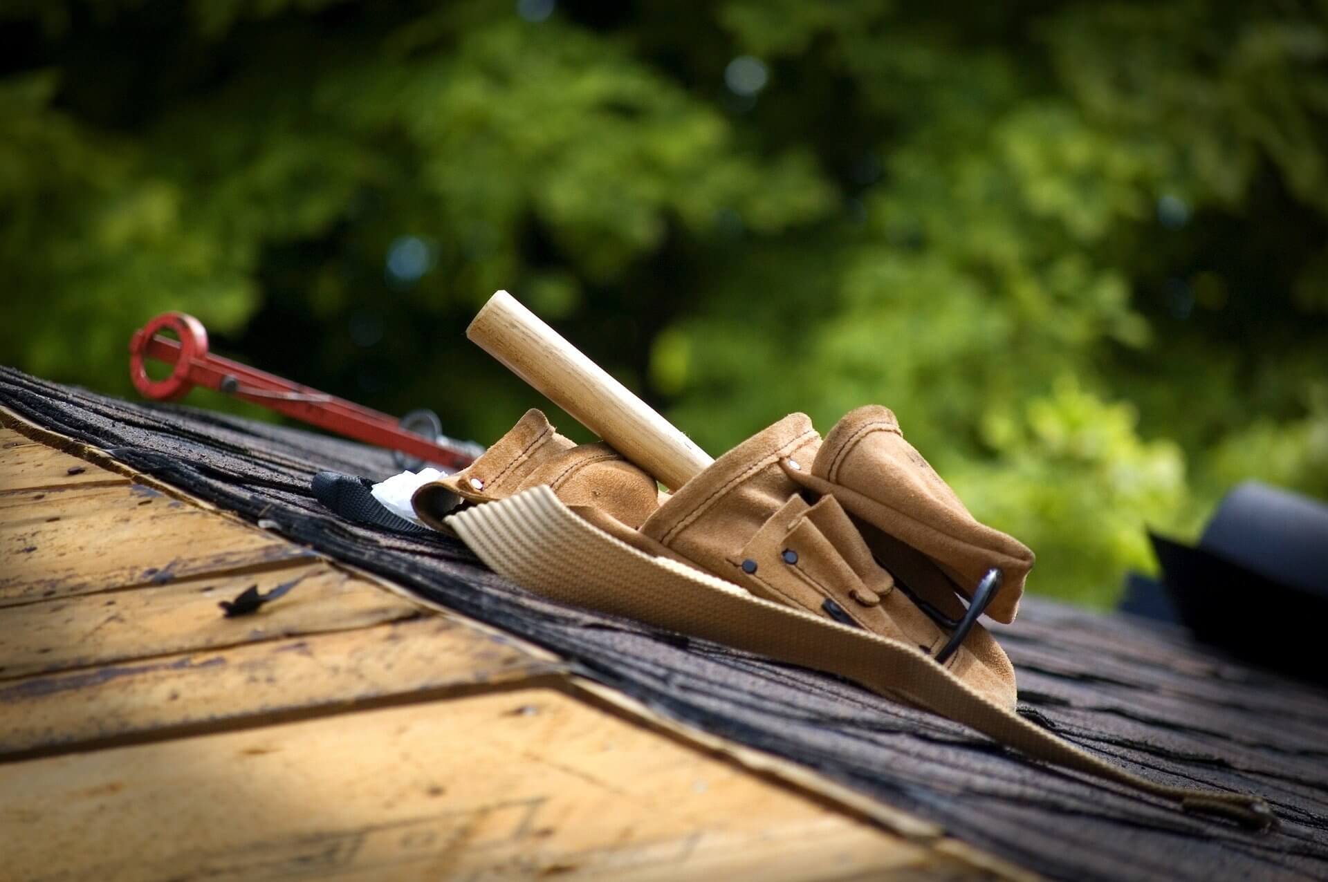 Stock image of a toolbelt on a shingled roof.