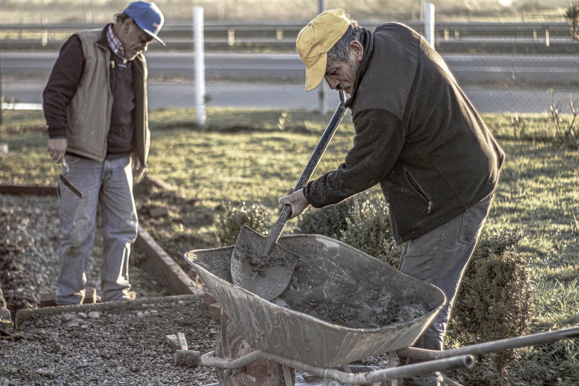 Man shoveling dirt out of wheelbarrow.